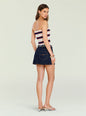 Back view of a model wearing a strapless white knit top with red and navy stripes, paired with a dark denim mini skirt. thumbnail image 5 of 5