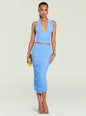 A model wearing a light blue ruched two-piece set consisting of a halter-neck crop top and a matching high-waisted midi skirt, holding a small gold clutch against a light gray studio background. thumbnail image 2 of 5