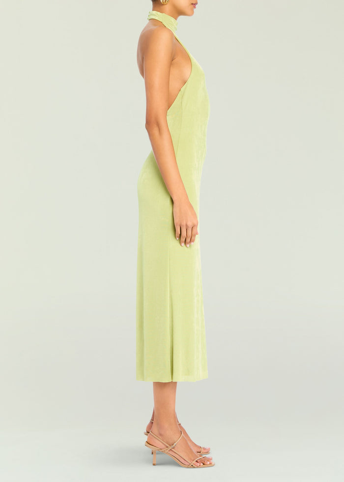 Side view of a lime green Carli Midi Dress with halter neckline and open back on a model wearing nude sandals.