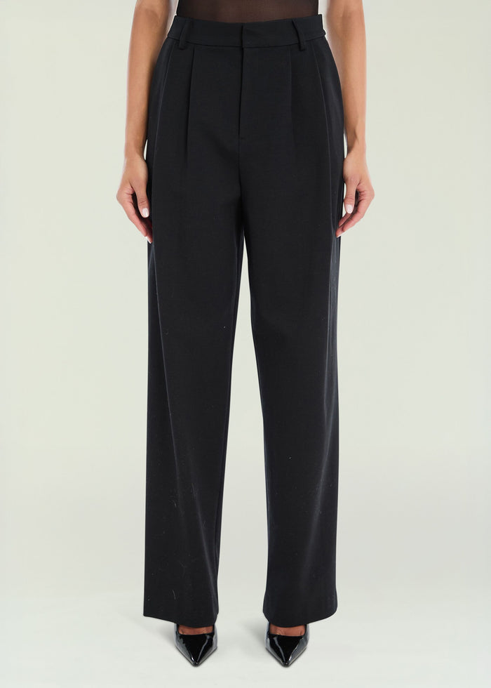 Front view of black Sonya pants with belt loops and a pleated front on a model.