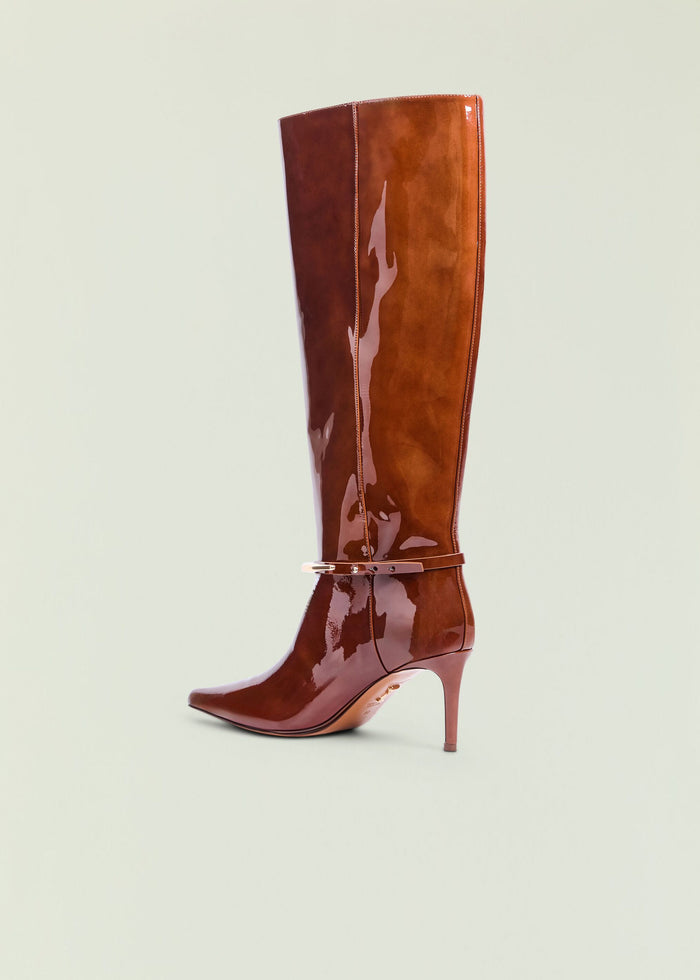 Glossy brown knee high boot with pointed toe, stiletto heel, and ankle strap.