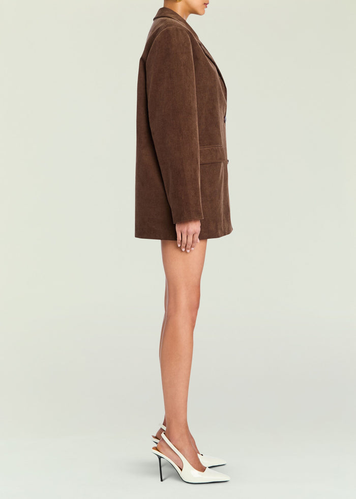 Side view of the brown Hera Corduroy Blazer on a model, mid thigh length with long sleeves and front pockets