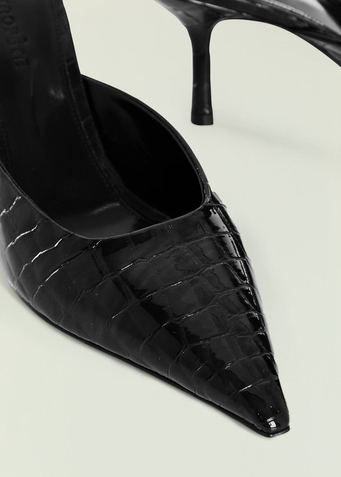 Close-up of a black crocodile-embossed kitten mule showing textured upper and pointed toe