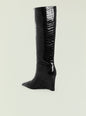 Natassa wedge boot in black crocodile-embossed leather shown from the side with pointed toe and wedge heel. thumbnail image 3 of 5