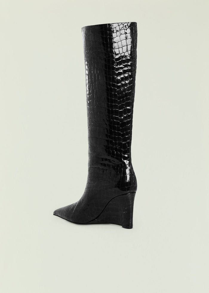 Natassa wedge boot in black crocodile-embossed leather shown from the side with pointed toe and wedge heel.