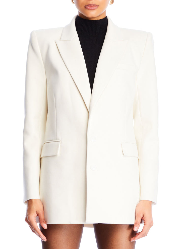 White Acadia blazer on a model worn over a black turtleneck with notched lapels and structured shoulders.