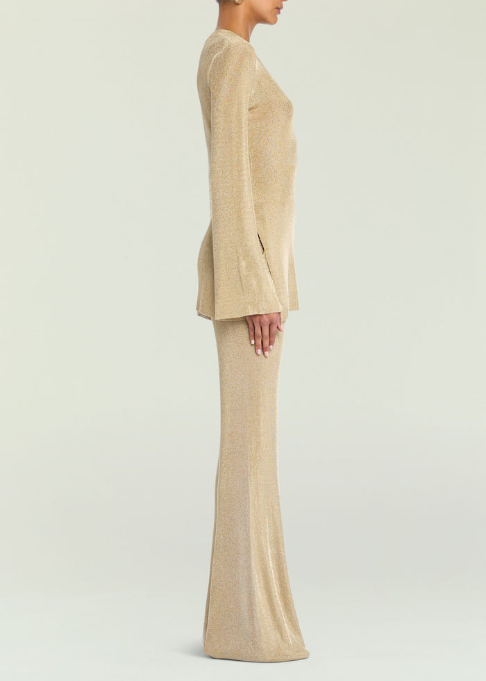 Side view of a model in a gold metallic knit top with matching knit pants.
