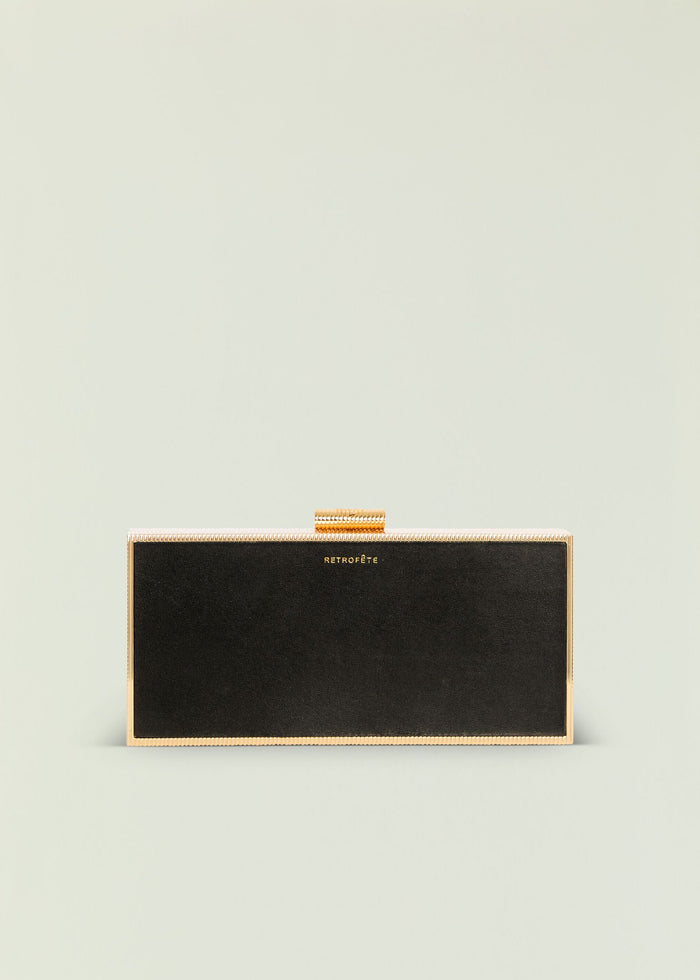 Milo Clutch black with gold metal frame displayed against a pale backdrop.