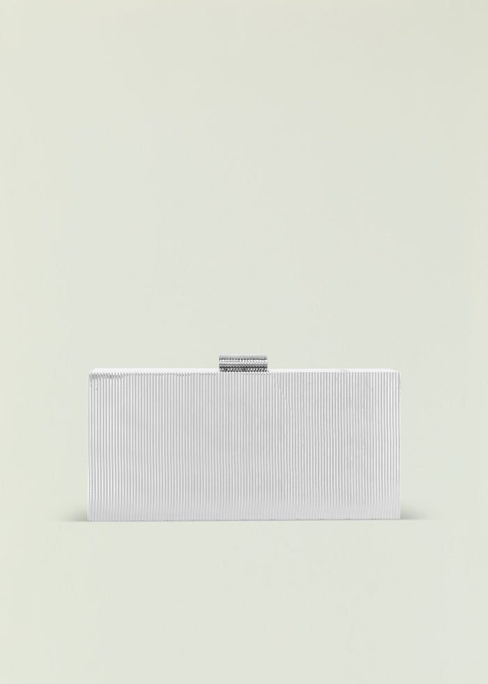 Milo Clutch in silver ribbed metal with a small curved clasp on top against a pale background.