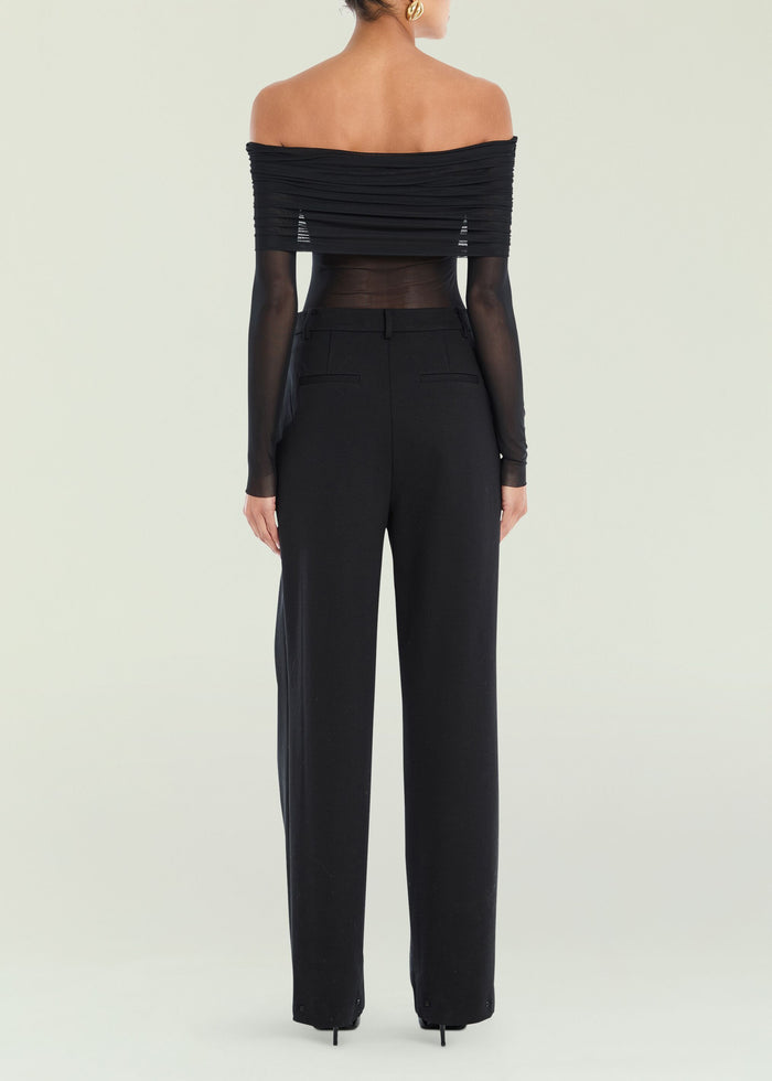 Back view of Rosa Top on a model, off the shoulder black top with ruched bands and sheer sleeves, paired with black pants.