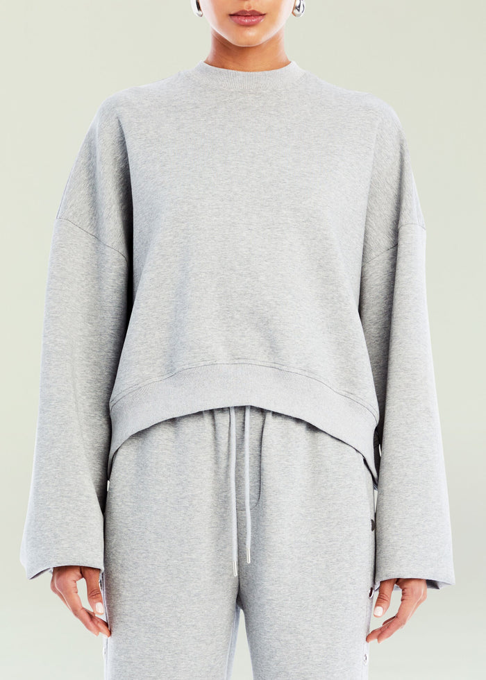 Front view of a model wearing a light grey Calla Sweatshirt with a relaxed fit