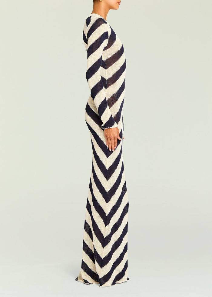 Side view of a model in the Rubi Knit Maxi Dress with bold navy and cream diagonal stripes.