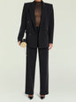 Model in a black tailored double breasted suit with a sheer top, holding a round gold handbag. thumbnail image 2 of 5