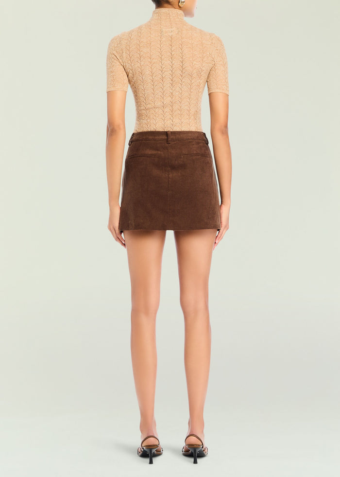 Back view of a model wearing a brown corduroy mini skirt with a beige lace top