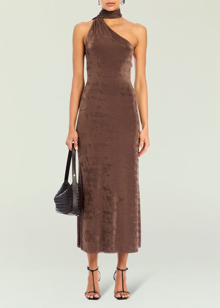 Brown velvet Tre Midi Dress front view with a wrapped one shoulder neckline and neck wrap, model carrying a black woven handbag