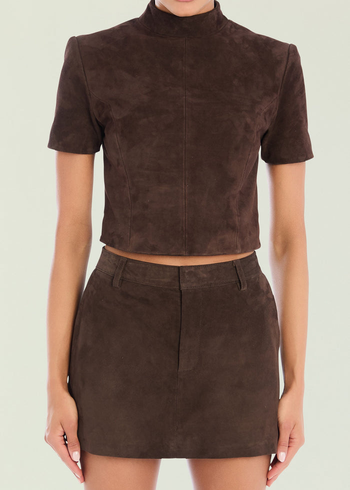 Close up of a brown suede high neck top with short sleeves and visible seam details