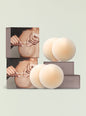 Packaging for no show nipple covers with beige silicone disks displayed beside stacked boxes. thumbnail image 1 of 2
