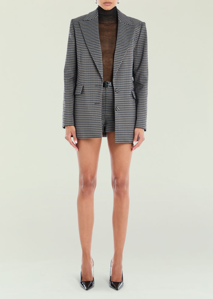 Walter blazer in grey and black check with notch lapels worn over a brown turtleneck and matching check shorts.