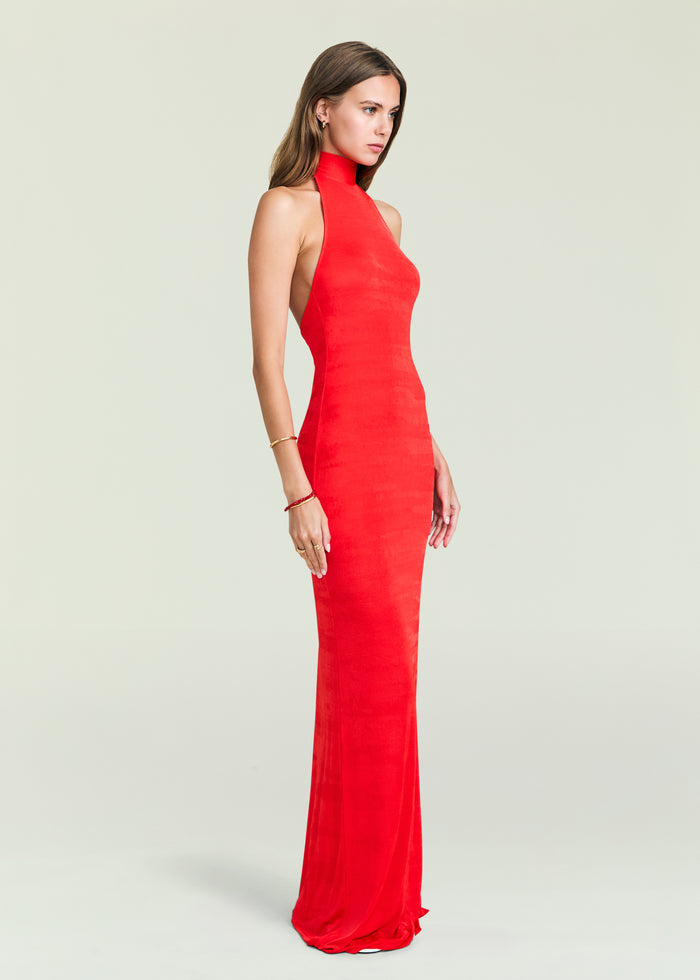Model in a bold red Lucky Maxi Dress with a high neck and floor length silhouette.