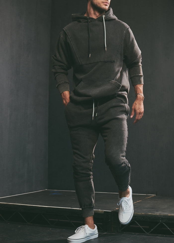 Male model wearing a dark Trent Jogger hoodie and matching joggers with white sneakers